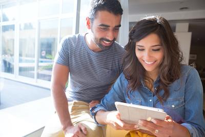 A smiling couple looking at their ipad