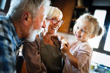 Grandparents laughing with their granddaughter in the kitchen