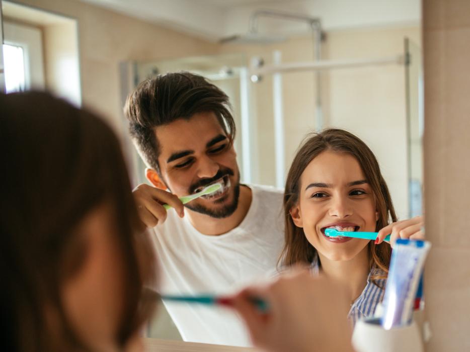 Two people brushing their teeth to prevent gum disease