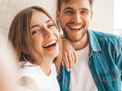 A laughing couple leaning against a wall | dentist Corona, CA