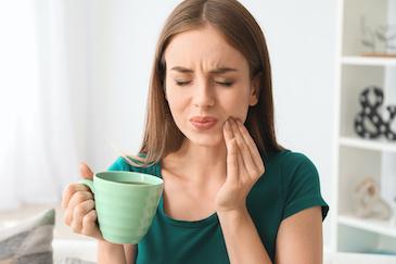 A woman with tooth pain while drinking hot tea