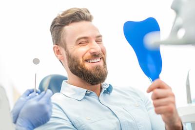 A man looking at his teeth in the mirror