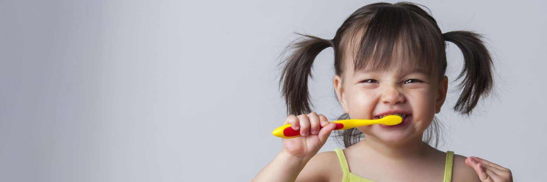 A smiling child brushing her teeth