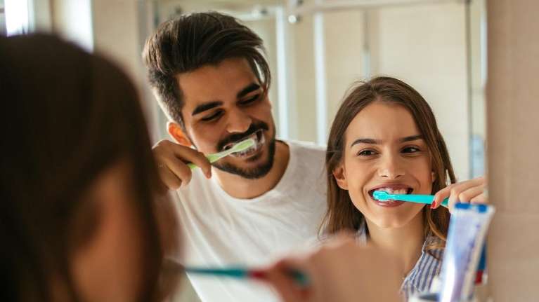 A father and his daughter brushing their teeth in the mirror
