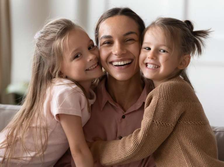 A mother and her two daughters smiling