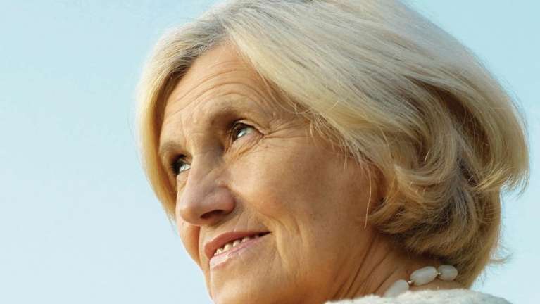 An older woman smiling outside | dentures Corona, CA