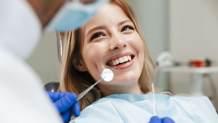 A smiling woman getting a dental exam | Dentist Corona CA