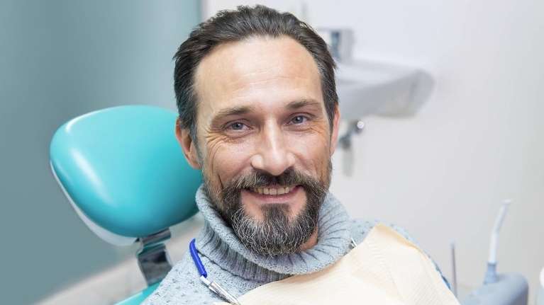 A smiling man sitting in a dental exam room