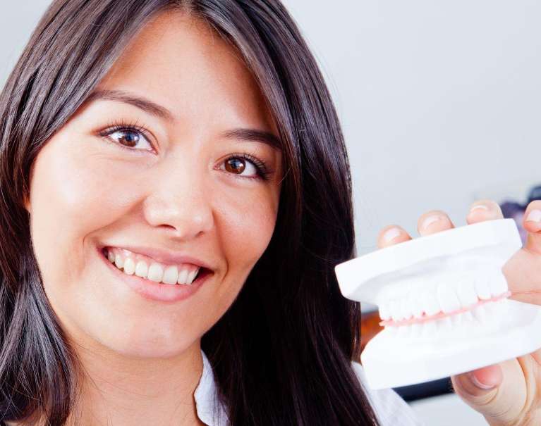 A smiling woman holding a dental mold