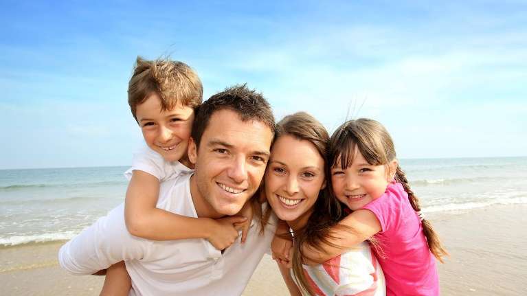 A smiling family at the beach | dental checkup Corona, CA