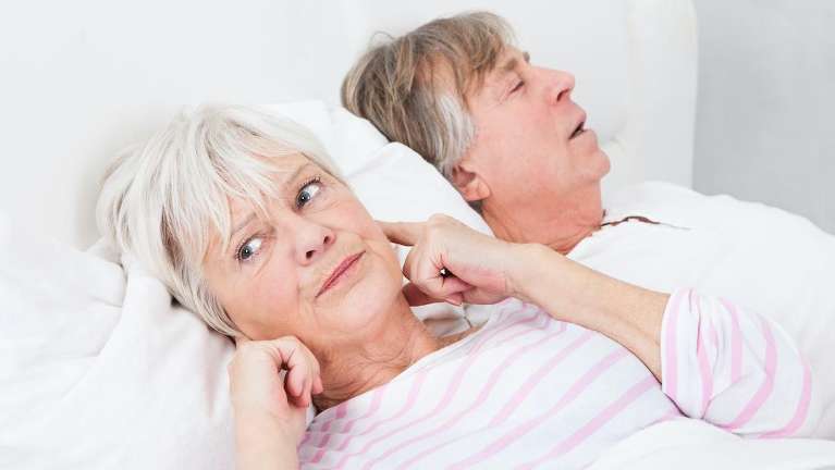 A woman bothered by her husband's sleep apnea related snoring in Corona, CA