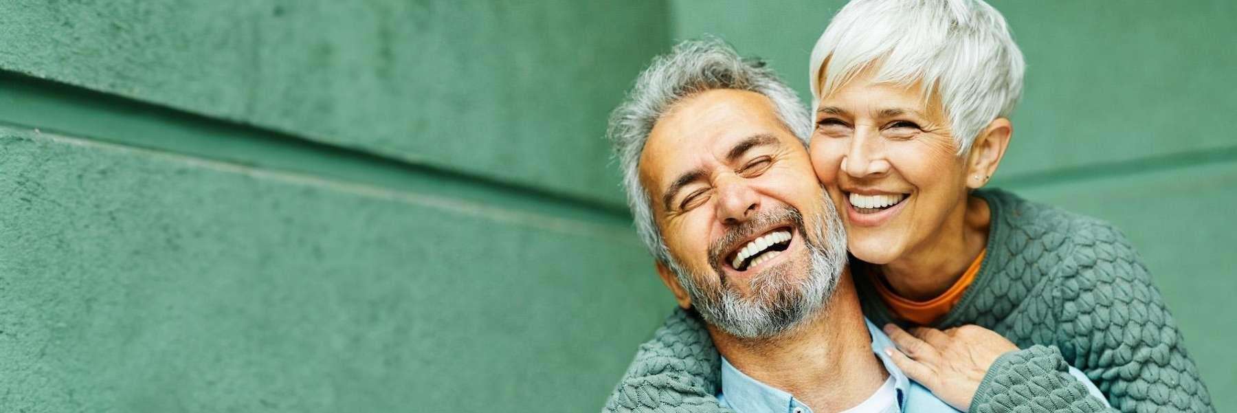 A smiling couple in front of a green wall